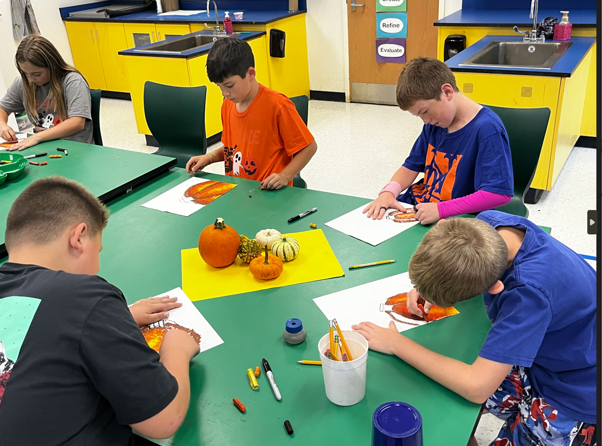 students sitting at table drawing pumpkins 